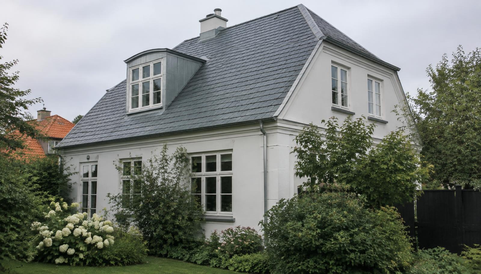 Ældre hvid villa med naturskifertag og kvist med zinkinddækning